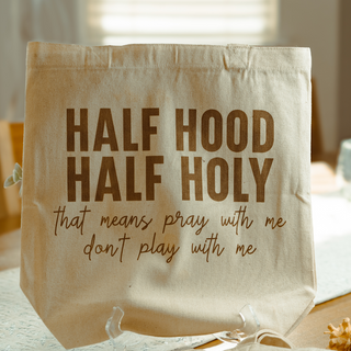 Beige tote bag with humorous text on a blurred indoor background
