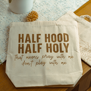 Beige tote bag with humorous text on a wooden surface