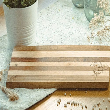 Wooden cutting board on a textured surface with decorative elements