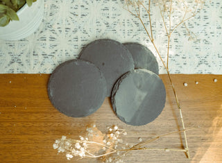 Slate gray circular coasters on a wooden surface with a textured white background