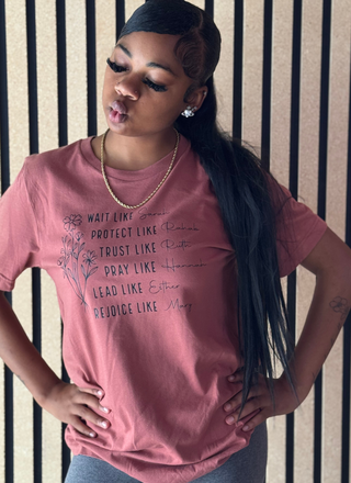 Woman wearing a pink t-shirt with text against a striped wall.